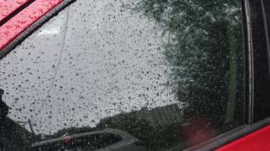 Yağmur sırasında su damlaları bir arabanın yan camından aşağı yuvarlanır..