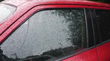 Yağmur sırasında su damlaları bir arabanın yan camından aşağı yuvarlanır..