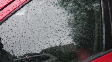 Yağmur sırasında su damlaları bir arabanın yan camından aşağı yuvarlanır..