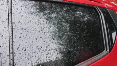 Yağmur sırasında su damlaları bir arabanın yan camından aşağı yuvarlanır..