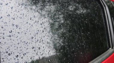 Yağmur sırasında su damlaları bir arabanın yan camından aşağı yuvarlanır..