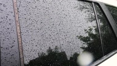 Yağmur sırasında su damlaları bir arabanın yan camından aşağı yuvarlanır..