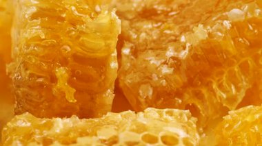 Altın ballı bal peteği parçaları beyaz bir tabakta dönüyor. Balmumu hücrelerini arı balı ile kapatın. Makro atış. Sağlıklı yeme kavramı.