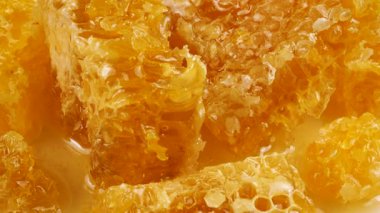 Altın ballı bal peteği parçaları beyaz bir tabakta dönüyor. Balmumu hücrelerini arı balı ile kapatın. Makro atış. Sağlıklı yeme kavramı.