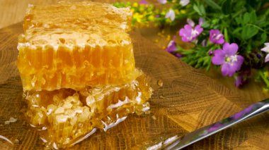 Tahta bir meşe ağacını baldan tahıl kesme tahtasını bıçakla kepçeleyip bal peteğine aktararak temizlemek. Balmumu hücrelerini arı balı ile kapatın. Sağlıklı yeme kavramı.