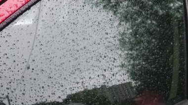 Yağmur sırasında su damlaları bir arabanın yan camından aşağı yuvarlanır..
