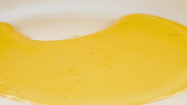 Altın bal damlaları beyaz bir tabağa damlar ve bal birikintisi oluşturur. Sağlıklı yeme kavramı.