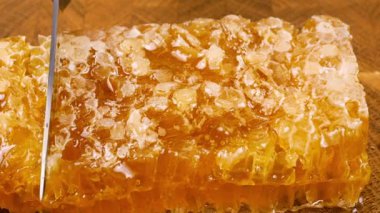 Bal peteklerini, meşe ağacından yapılmış tahıl kesme tahtasına karşı bıçakla kesmek. Sağlıklı yeme kavramı.