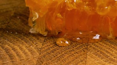 Tahta bir meşe ağacının ucunda, kaşıkla kesilmiş bir tahtanın üzerinde duran tarağın içindeki bir parça altın balı kırmak. Balmumu hücrelerine yakın çekim. Sağlıklı yeme kavramı.