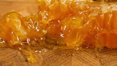 Tahta bir meşe ağacının ucunda, kaşıkla kesilmiş bir tahtanın üzerinde duran tarağın içindeki bir parça altın balı kırmak. Balmumu hücrelerine yakın çekim. Sağlıklı yeme kavramı.