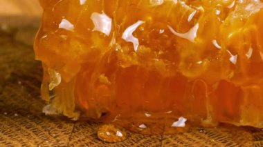 Tahta bir meşe ağacının ucunda, kaşıkla kesilmiş bir tahtanın üzerinde duran tarağın içindeki bir parça altın balı kırmak. Balmumu hücrelerine yakın çekim. Sağlıklı yeme kavramı.