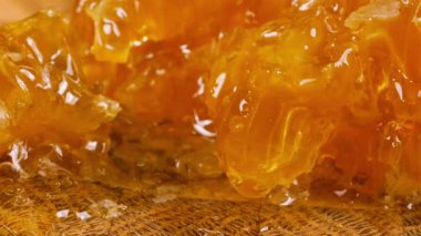 Tahta bir meşe ağacının ucunda, kaşıkla kesilmiş bir tahtanın üzerinde duran tarağın içindeki bir parça altın balı kırmak. Balmumu hücrelerine yakın çekim. Sağlıklı yeme kavramı.