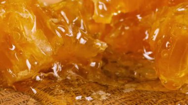 Tahta bir meşe ağacının ucunda, kaşıkla kesilmiş bir tahtanın üzerinde duran tarağın içindeki bir parça altın balı kırmak. Balmumu hücrelerine yakın çekim. Sağlıklı yeme kavramı.