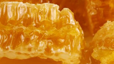 Altın ballı bal peteği parçaları beyaz bir tabakta dönüyor. Balmumu hücrelerini arı balı ile kapatın. Makro atış. Sağlıklı yeme kavramı.