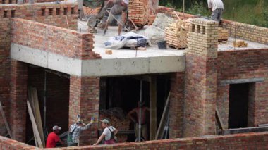 LVIV, UKRAINE - 21 Temmuz 2025: inşaat alanı. İnşaat işçileri tuğlalardan bir evin duvarını inşa ediyorlar..