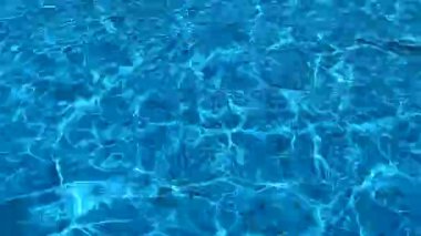 Parlak güneşli bir günde mavi suyun berrak yüzeyinde hafif dalgalar olur..