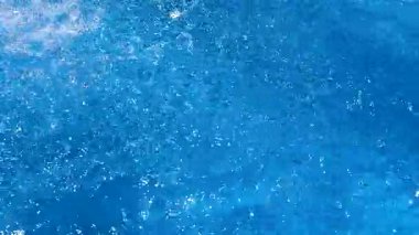 Mavi suyun berrak yüzeyinde hafif dalgalar ve parlak güneşli bir günde biraz su..