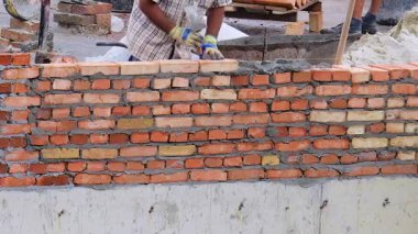 İnşaat alanı. İnşaat işçileri tuğlalardan bir evin duvarını inşa ediyorlar..