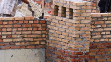 İnşaat alanı. İnşaat işçileri tuğlalardan bir evin duvarını inşa ediyorlar..