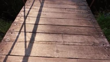 Göletin üzerinde metal parmaklıklar olan tahta bir köprü..