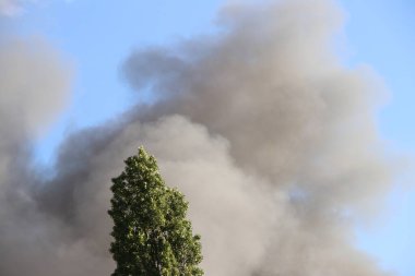 Berlin 'in Spandau bölgesindeki bir yangından yükselen kalın gri duman. Duman bulutları aktif bir acil durum sinyali veriyor, uzaktan görülebilir. .