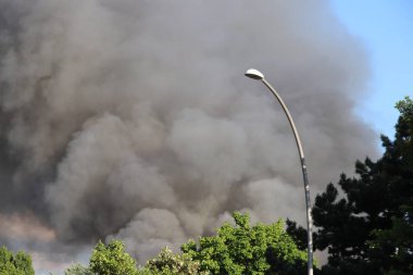 Berlin 'in Spandau bölgesindeki bir yangından yükselen kalın gri duman. Duman bulutları aktif bir acil durum sinyali veriyor, uzaktan görülebilir. .