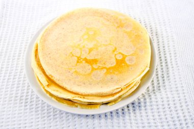 Beyaz masa örtüsü üzerinde krep olan bir tabak.