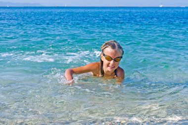 Kız denizde yüzmeyi öğreniyor.