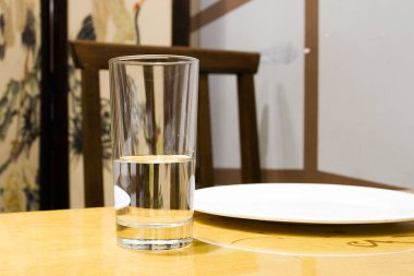 Bej arkaplanda bir masanın üzerinde bir bardak su.