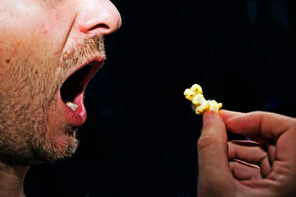 profile of a man with an open mouth eating popcorn