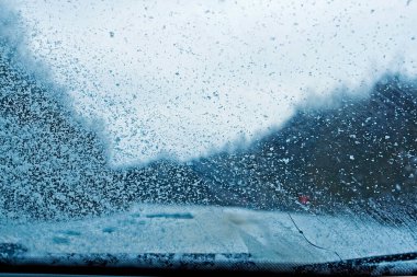 Kışın yolda donmuş bir ön camda kar.
