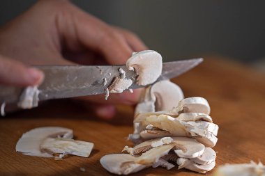 cut thin slices of champignon gibs on a cutting board with a sharp knife. Kitche