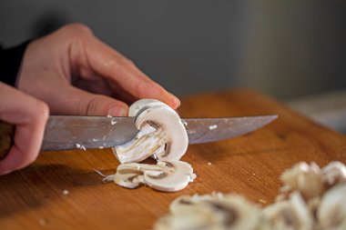 cut thin slices of champignon gibs on a cutting board with a sharp knife. Kitche