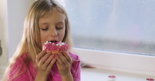 Happy Little Blonde Girl Pink Eats Pink Donut Icing Window — Stok video