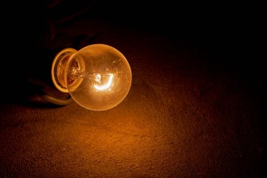 weakly burning electric light bulb in the dark near the wall. blackout, bomb shelter.