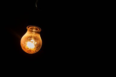 weakly burning electric light bulb in the dark. Electricity