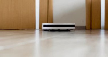 robot vacuum cleaner at speed cleans the floor near the legs of the sofa in the room, horizontal