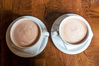 white cups with hot latte coffee on a wooden table. flatley