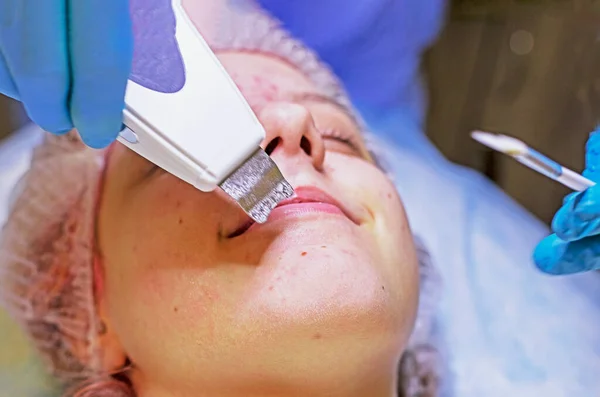 beautician cleans the face of a happy young girl with a laser, horizontal