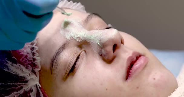 Cosmetólogo Aplica Una Máscara Color Verde Claro Curativo Con Cepillo — Vídeos de Stock