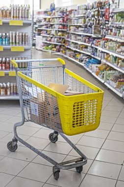 Alışveriş merkezinde el işi kutuları olan tam sarı market arabası.