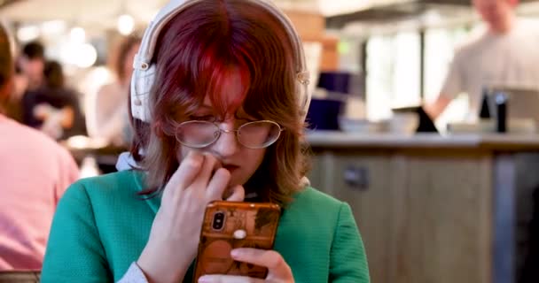 Tenager Dziewczyna Jasnymi Czerwonymi Włosami Okularach Obgryzając Paznokcie Patrząc Gadżet — Wideo stockowe