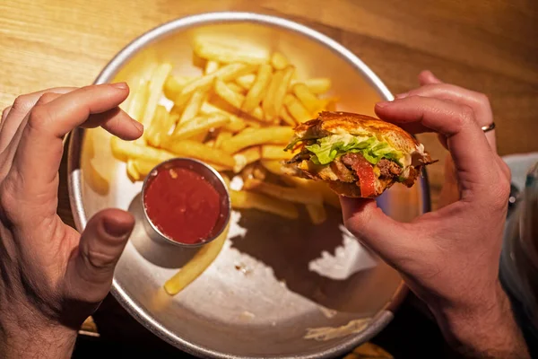 Mâinile Omului Țin Bucată Hamburger Peste Farfurie Cartofi Prăjiți Ketchup — Fotografie, imagine de stoc