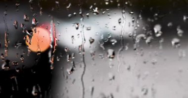 Siyah bir arabanın silueti yağmurlu havada dönüyor, görüş mesafesi zayıf..