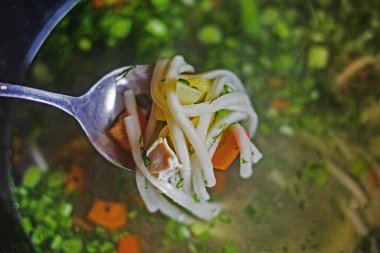 Sebze çorbasının arka planında havuç ezmeli ve tavuk parçalı tam kaşık. Evde yemek yapmak.