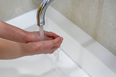 Çocuk enfeksiyon ve virüslerden kaynaklanan su basıncıyla ellerini iyice yıkıyor. koronovirüs