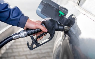 Benzin istasyonunda yakıt ikmali yapıyorum. Depoyu dolduran ve benzini dolduran adam benzin istasyonunda benzinle arabayı yağlıyor. Benzin istasyonunda yakıt ikmali. İstasyonda yakıt pompası