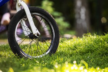 Akşam güneşiyle aydınlatılan bir çocuk bisikletinin tekerleğine yakın çekim. Bisiklet ve eğitim. turizm