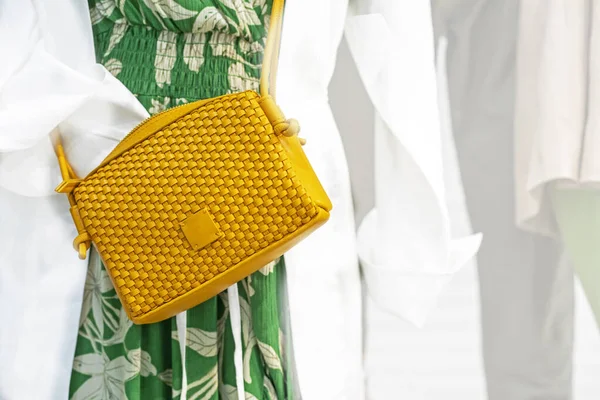 yellow fashionable woven clutch bag on a chintz green dress. Fashion everyday