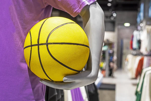 mannequin holding a yellow basketball in a sporting goods store